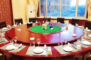 Una mesa redonda con un espacio verde central, rodeada de sillas y dispuesta con platos, vasos y cubiertos.