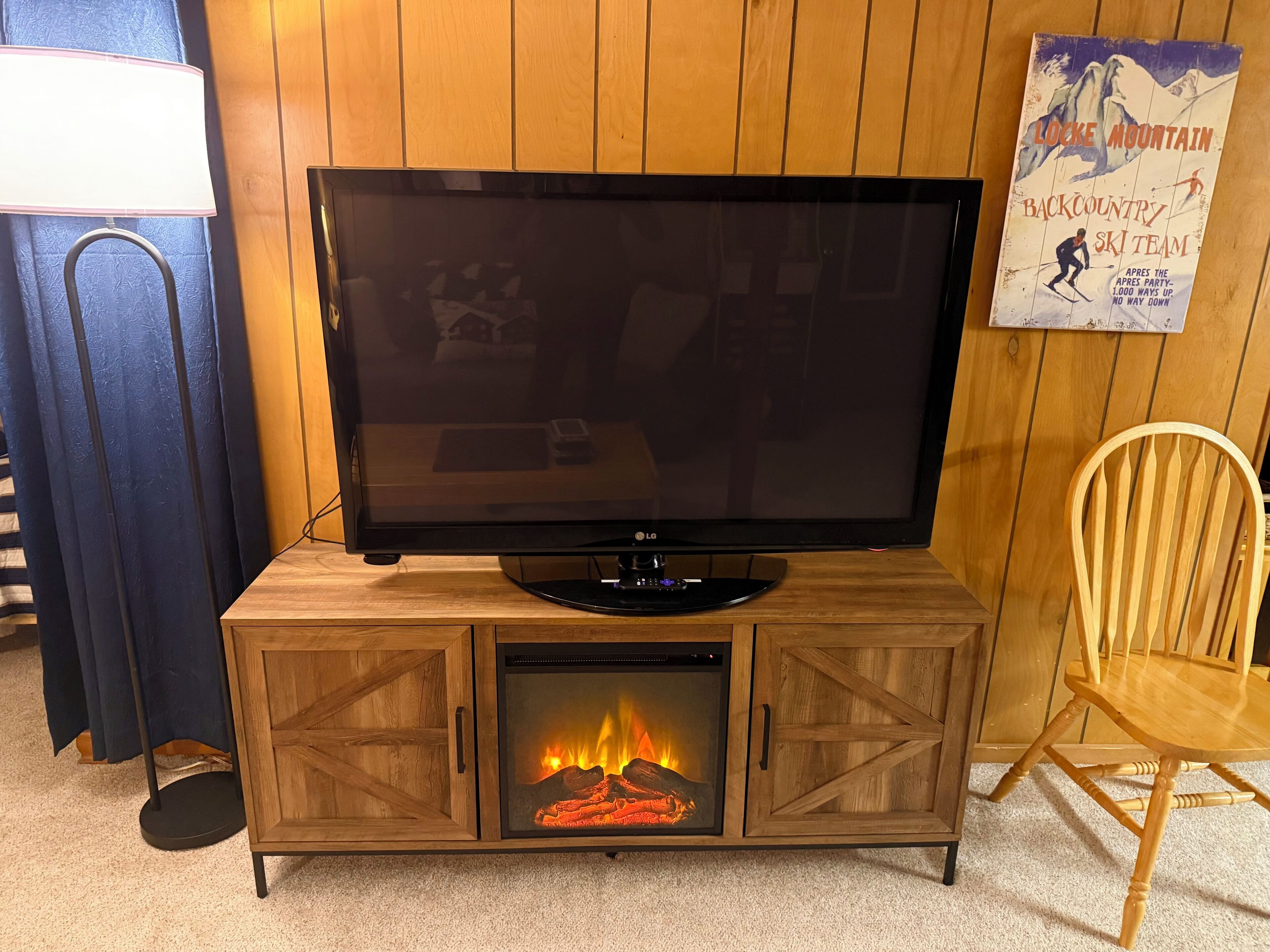 A television on a wooden cabinet with a fireplace below it.