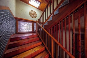 Una escalera de madera con diseño tradicional que conduce a una habitación con pared de ladrillo y un adorno mural.
