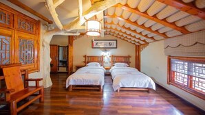 Una habitación tradicional con muebles de madera, dos camas y un techo inclinado con vigas a la vista.