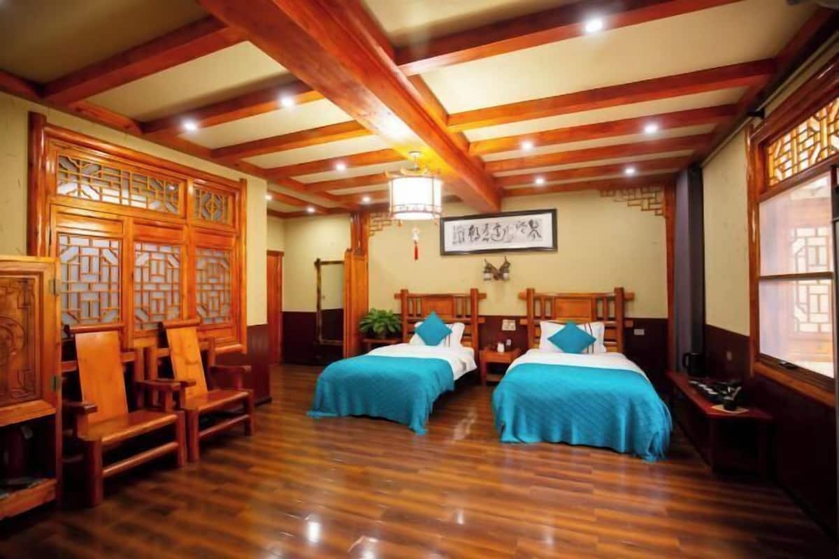 A traditional room with wooden furniture, two beds, a wooden ceiling, and a decorative screen.