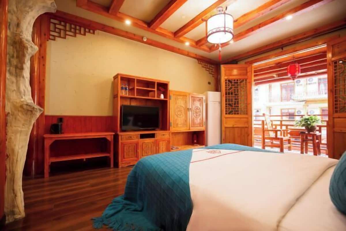 A traditional room with wooden furniture, a television, and a balcony with a view of the outside.