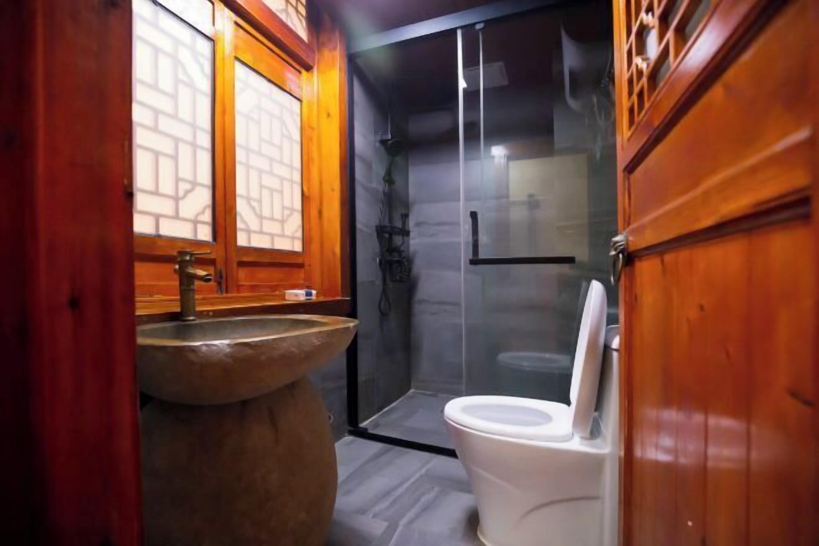 Een badkamer met een wasbak van natuursteen, een toilet en een douche met glazen wanden.