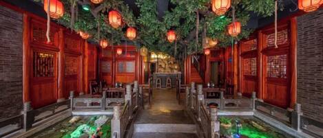 Un couloir de style chinois traditionnel, agrémenté de portes en bois, de lanternes et d’un élément décoratif aquatique.