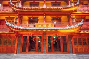 Un bâtiment traditionnel à plusieurs étages, doté d’une entrée imposante, de balcons et d’un éclairage décoratif.