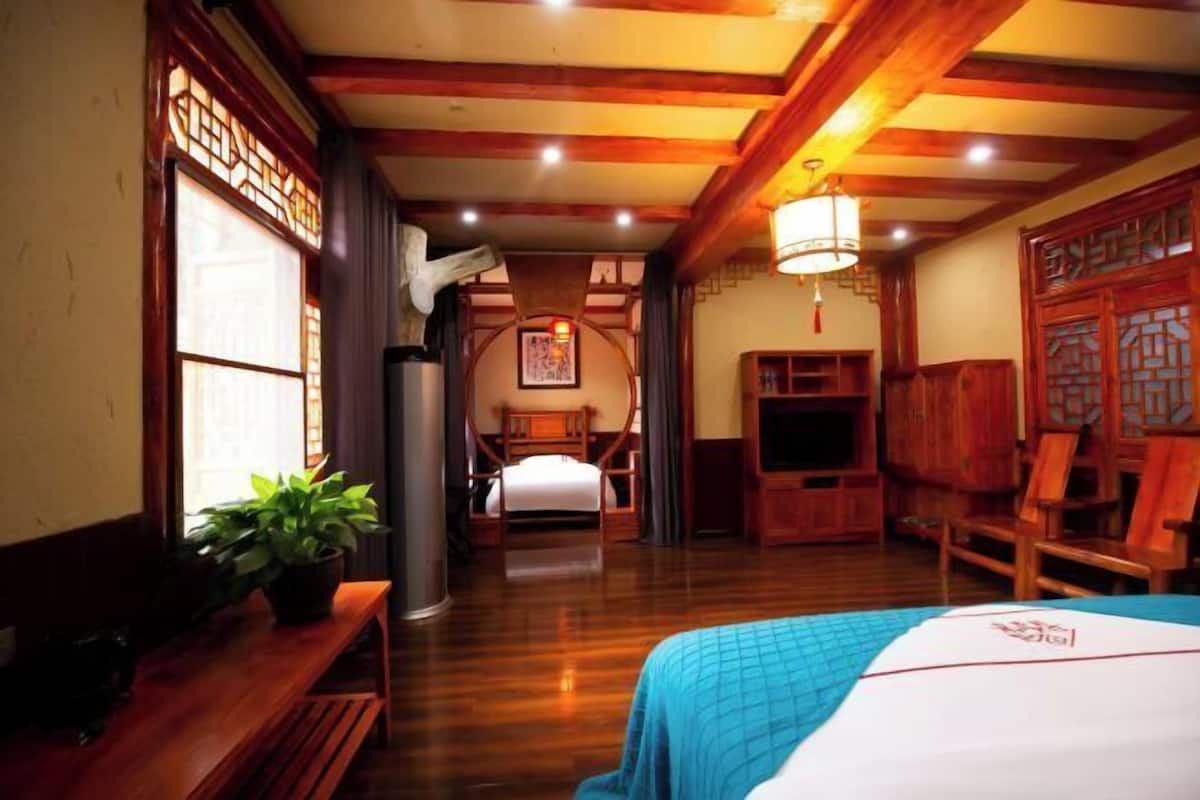 A traditional Japanese-style room with a bed, wooden furniture, and a view of a traditional Japanese building.