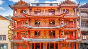 Un edificio tradicional de varios pisos con fachada simétrica, varios balcones y una entrada central con un portón decorativo.