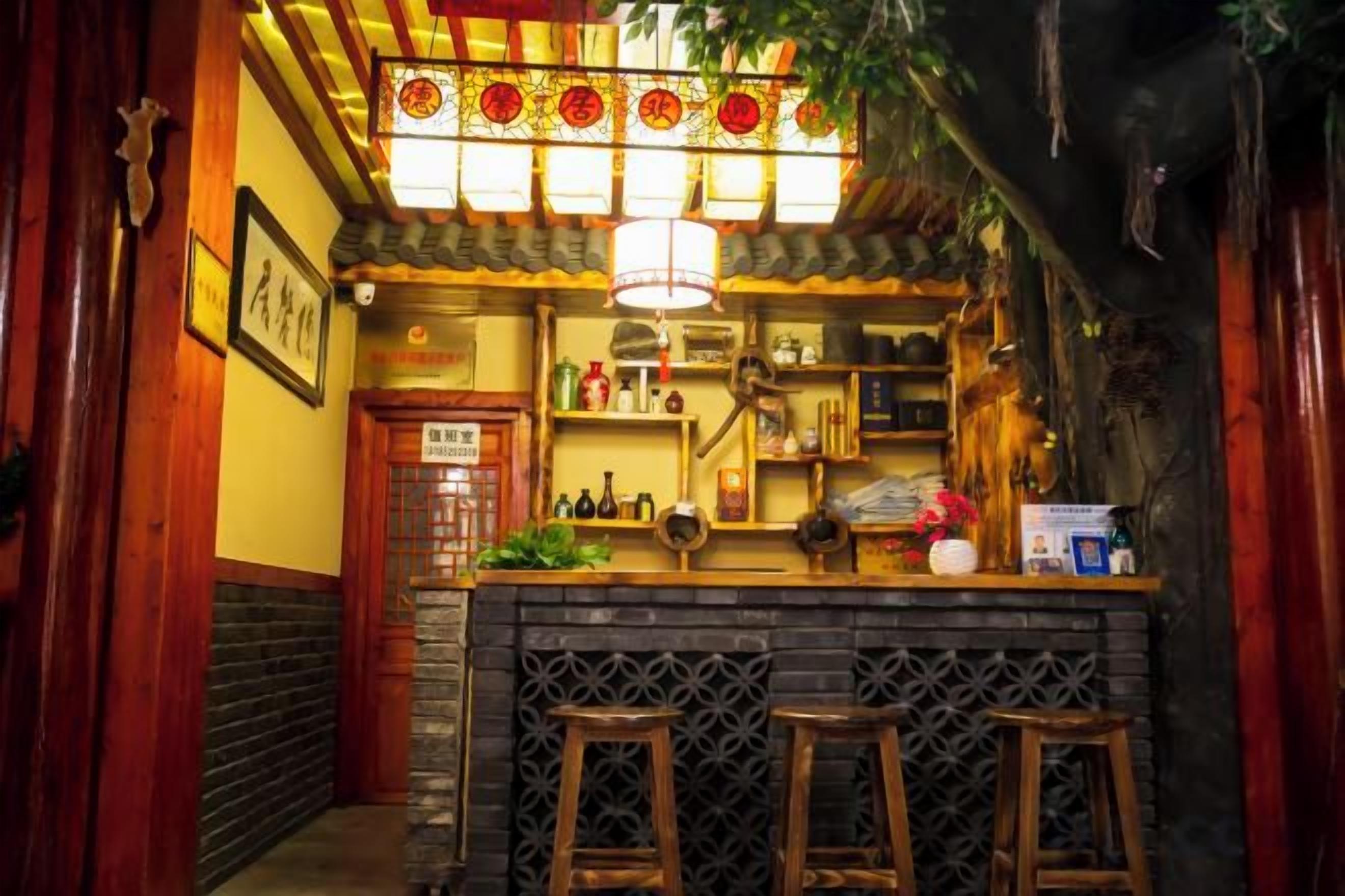 Uma área de bar com banquetas, prateleiras com garrafas e um lustre.