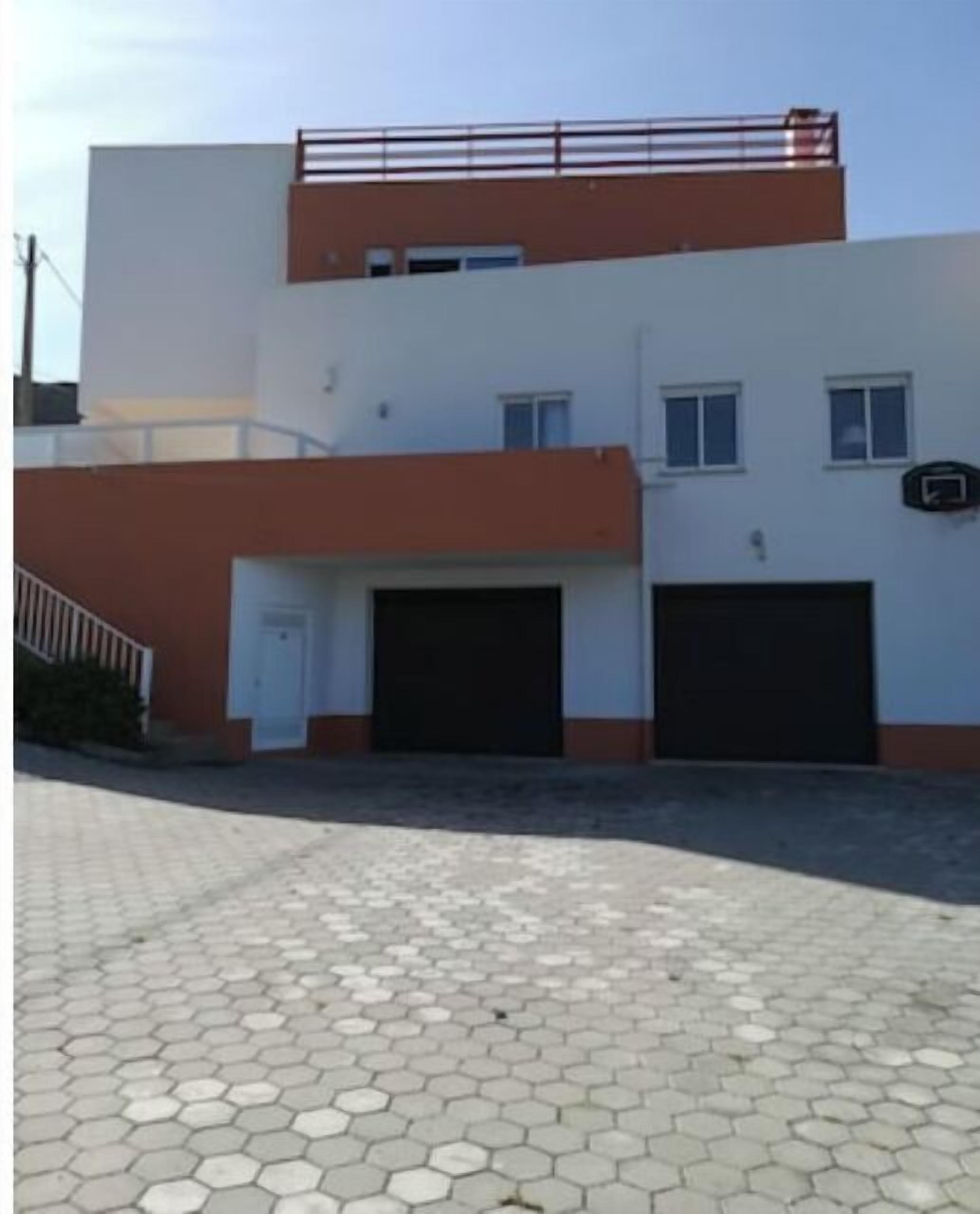 Un bâtiment à deux étages, doté d’un toit plat, de deux portes de garage et d’un petit balcon à l’étage supérieur.