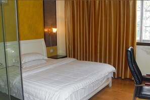 A bedroom with a bed, a nightstand, a chair, a glass partition, and a window with curtains.