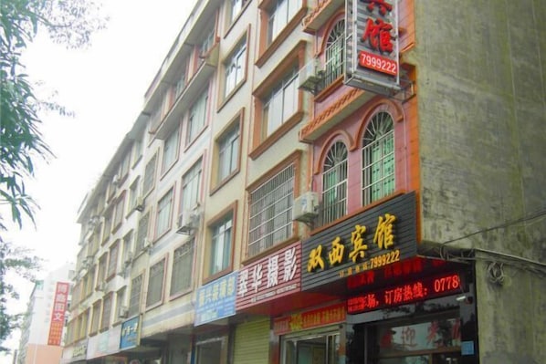 A multi-story building with various commercial establishments on the ground floor, including a cinema and a restaurant. - Shuangxi Hotel (Hechi)
