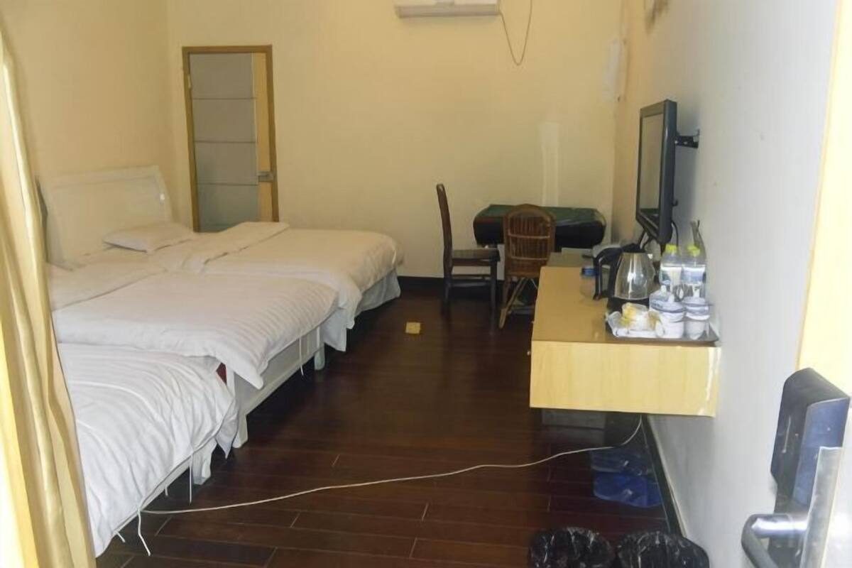 Une chambre avec trois lits, un bureau avec une chaise, un miroir et une petite table sur laquelle sont posés divers objets.