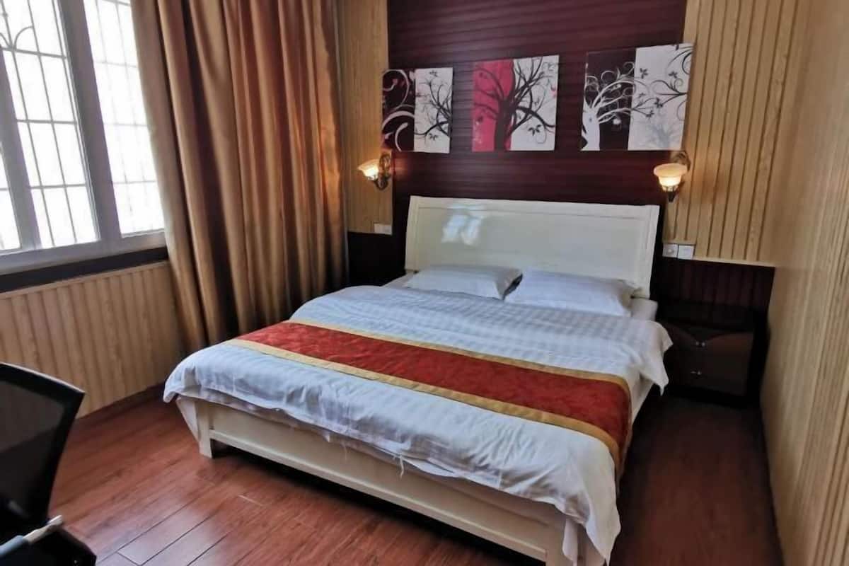 Une chambre d’hôtel avec un lit, une chaise, une table de chevet et des œuvres d’art accrochées au mur.