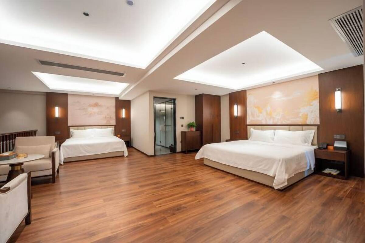 Una habitación de hotel moderna con dos camas, una zona de estar y un ventanal grande.