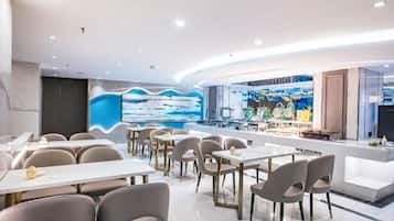 A modern restaurant with a curved counter, multiple tables, and chairs.