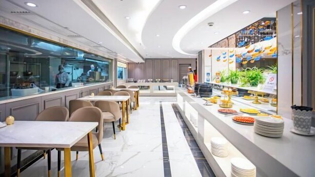 Un restaurante moderno con una barra larga, zona de estar y un separador de vidrio que divide el comedor de la cocina.