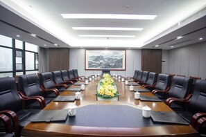 Un salón de conferencias con una larga mesa, varias sillas y un centro de mesa con flores.