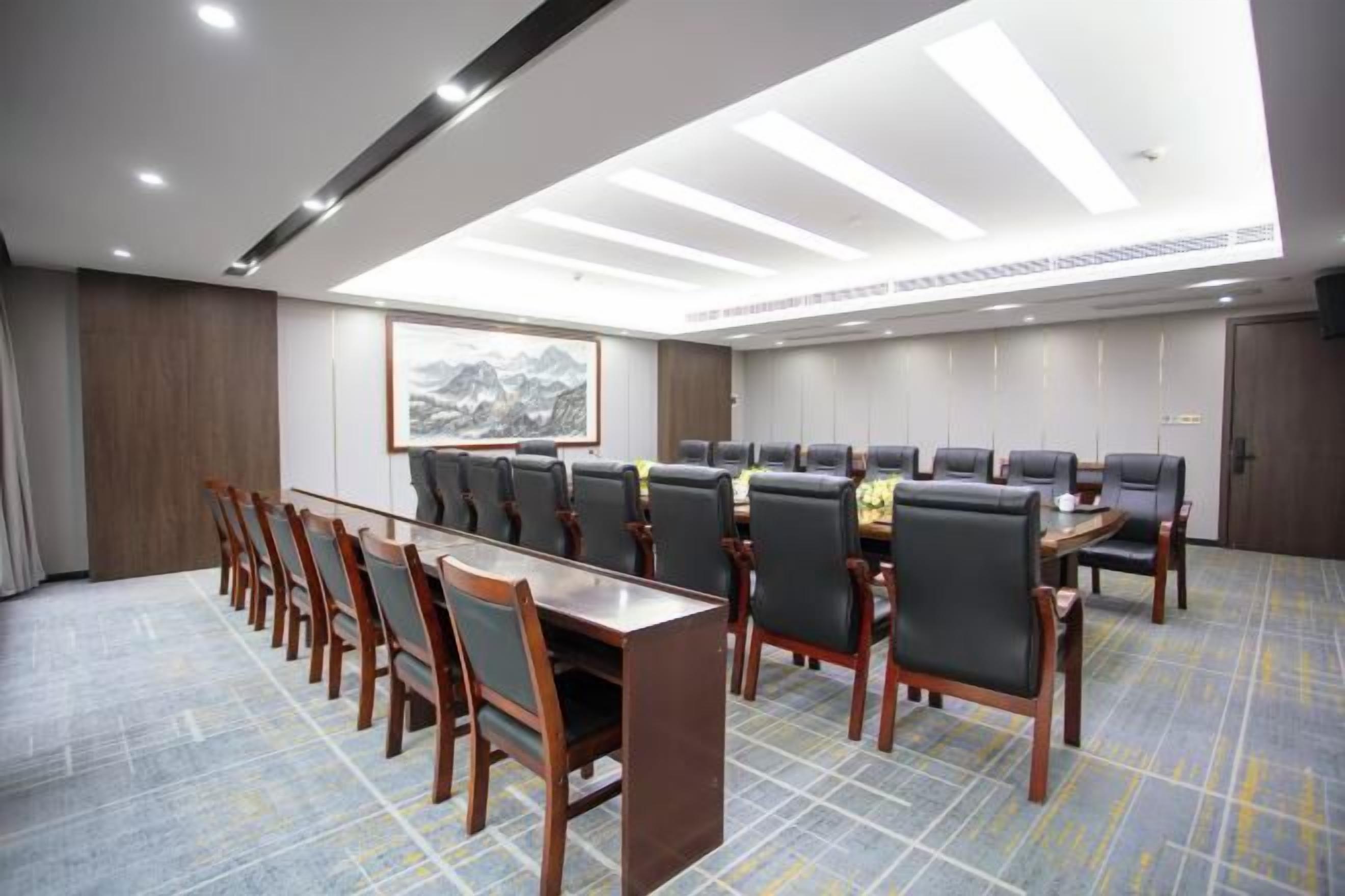 A conference room with a long table and chairs, a framed picture on the wall, and a carpeted floor.