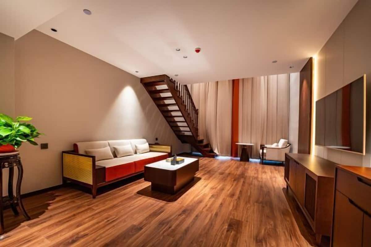 Una sala de estar moderna con piso de madera, un sofá, una mesa de centro y una escalera.