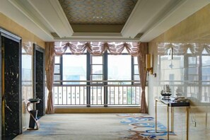 Une pièce spacieuse avec une grande fenêtre, une moquette à motifs et un plafond décoratif.