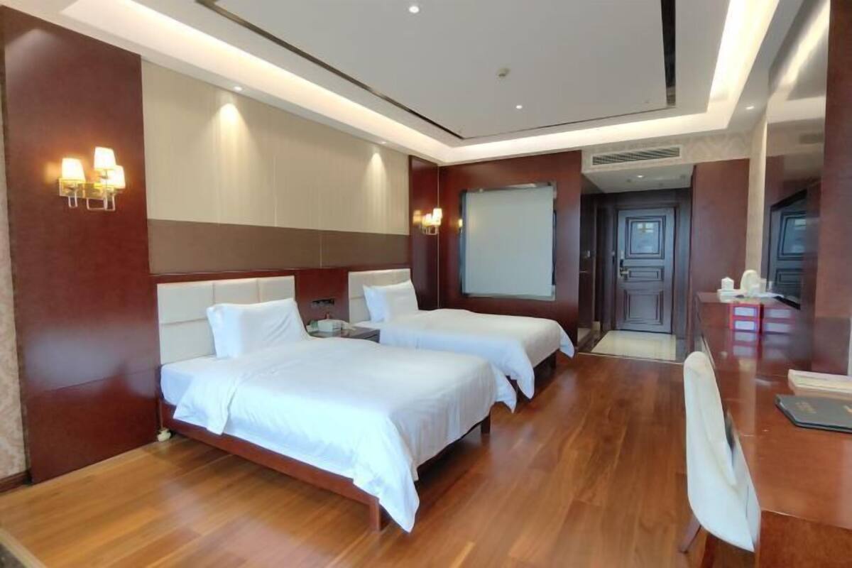 Habitación de hotel con dos camas, un escritorio y una pantalla de proyector.