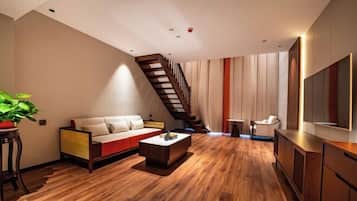Una sala de estar moderna con piso de madera, un sofá, una mesa de centro, un televisor y una escalera.