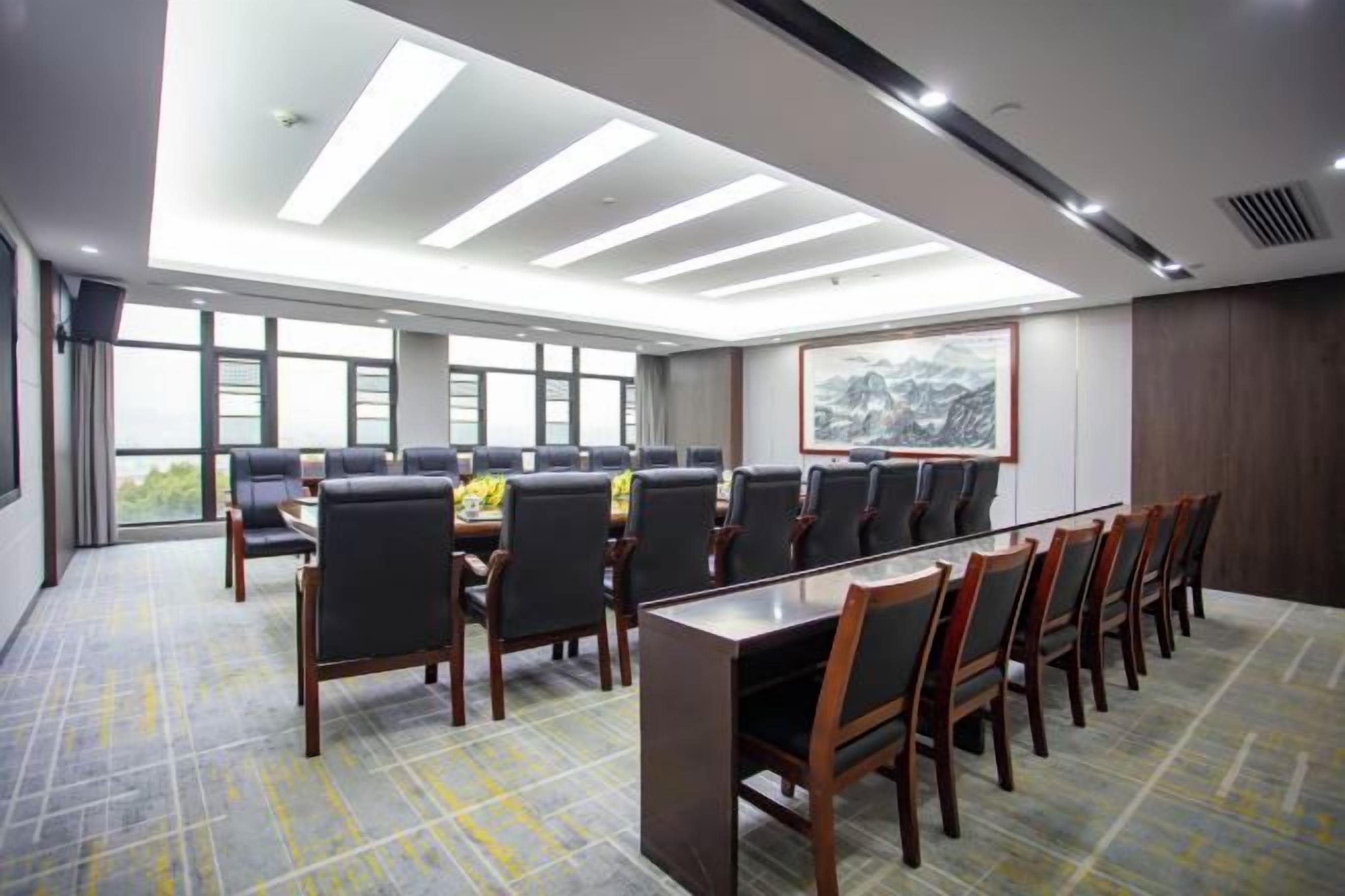 A conference room with a long table and chairs, large windows, and a view of the outdoors.