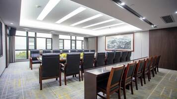 A conference room with a long table and chairs, large windows, and a view of the outdoors.