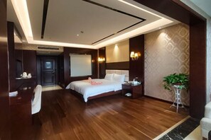 Una habitación de hotel con cama, mesita de noche, lámpara y una planta en maceta.