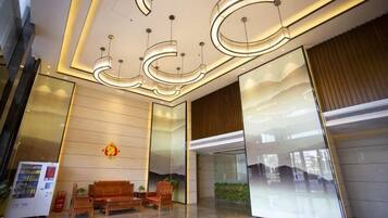 A modern lobby with a reception desk, seating area, and a large glass wall.