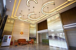 A modern lobby with a reception desk, seating area, and a large glass wall. - Yi Jia Hotel (Zhuhai)