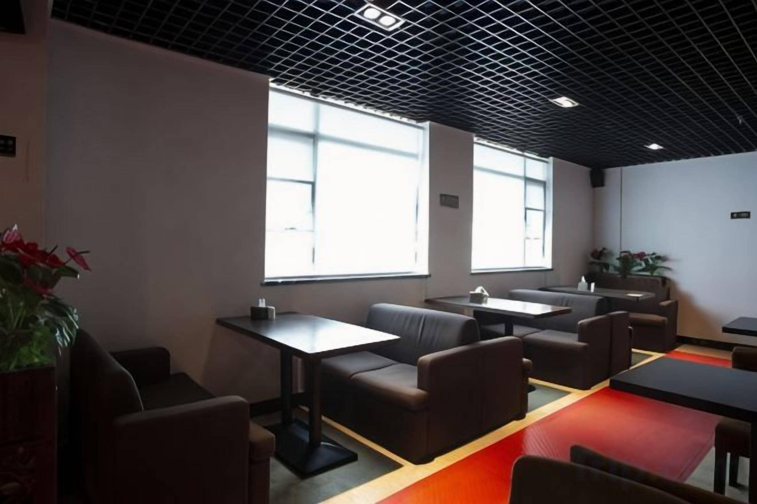 Un interior moderno con disposición de asientos, mesas y amplias ventanas que dejan entrar luz natural.