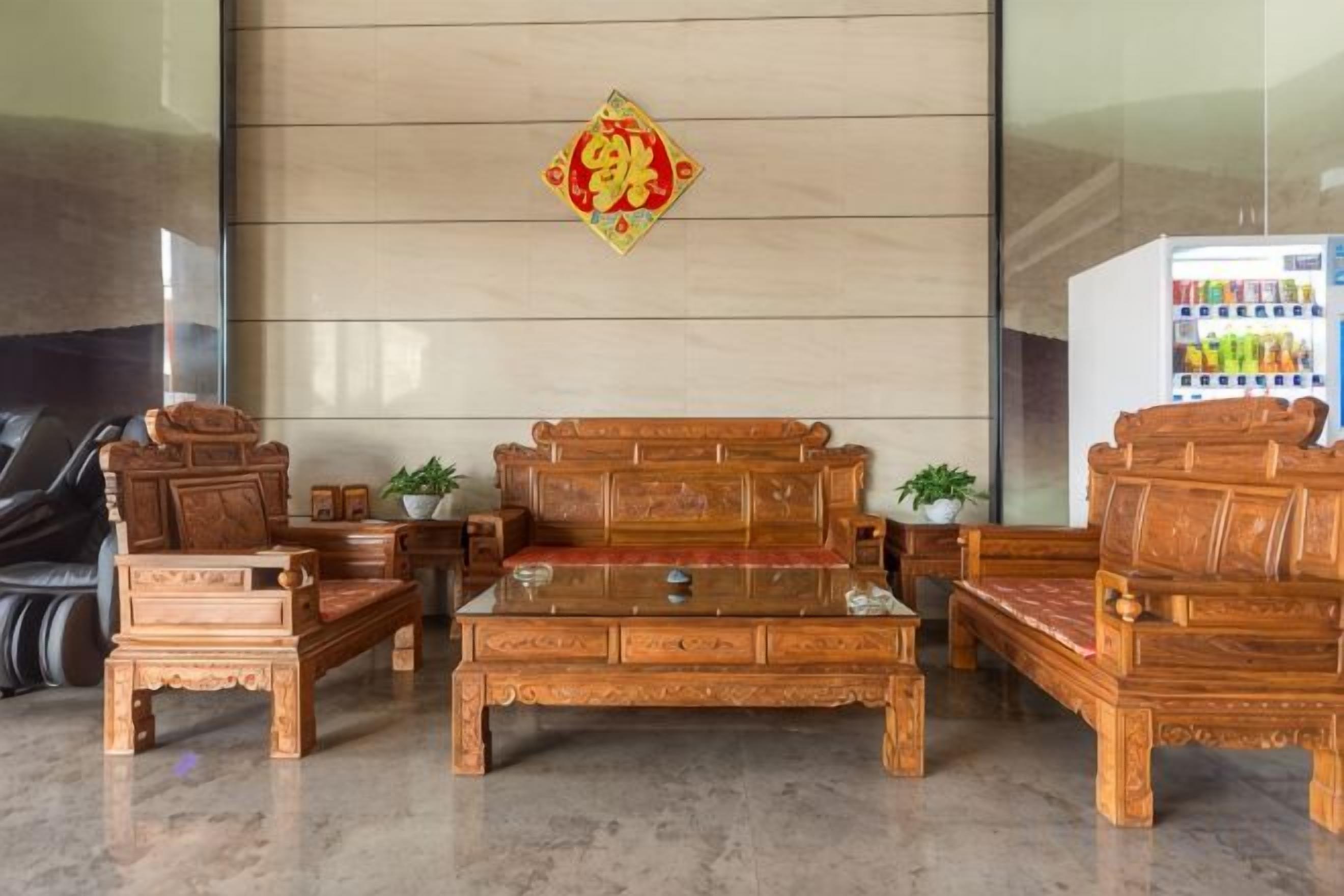 Ein traditionelles Holz-Sofa-Set mit Couchtisch, Kühlschrank und einer dekorativen Wandgestaltung.