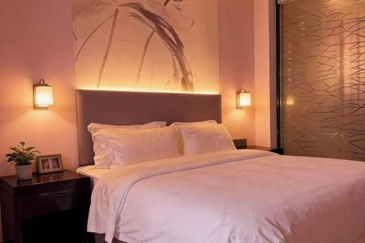 Un letto rifatto con cura, lenzuola bianche, una testiera e due lampade ai comodini.