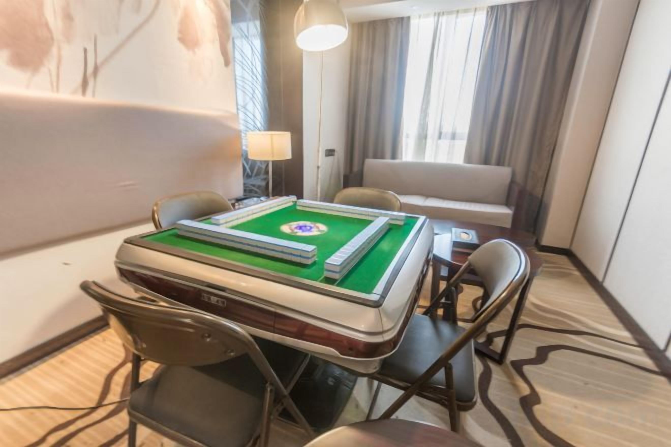 Habitación de hotel con mesa de billar, sofá y lámpara.