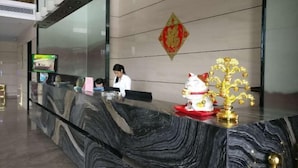 A reception desk with a marble top, a television screen, and a decorative golden tree. - Yi Jia Hotel (Zhuhai)