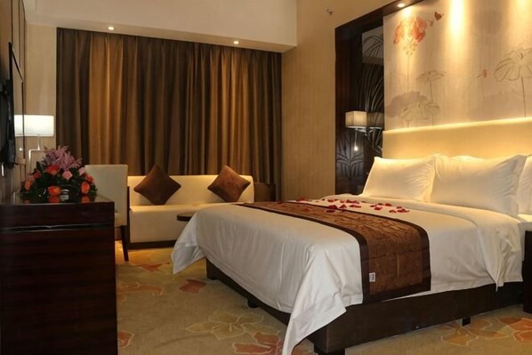 A hotel room with a bed, a sofa, a desk, and a large window with curtains. - Yi Jia Hotel (Zhuhai)