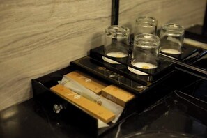 Un plateau noir avec trois photophores en verre et une boîte de mouchoirs.