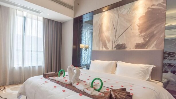 A hotel room with a large bed, a painting on the wall, and a window with curtains. - Yi Jia Hotel (Zhuhai)