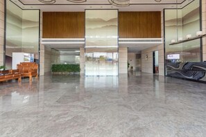 A spacious lobby with a marble floor, wooden paneling on the ceiling, and a reception desk. - Yi Jia Hotel (Zhuhai)