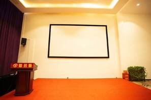 A room with a podium, a blank projection screen, and a red carpet. - Yi Jia Hotel (Zhuhai)
