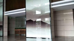 A modern lobby with a glass partition, a wooden panel wall, and a small plant display. - Yi Jia Hotel (Zhuhai)