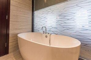 Une salle de bain moderne avec une baignoire sur pieds, une porte en bois et un mur orné de motifs géométriques en carreaux.