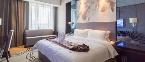 Habitación de hotel con una cama grande, un sofá, un escritorio y un cuadro abstracto de gran tamaño en la pared.