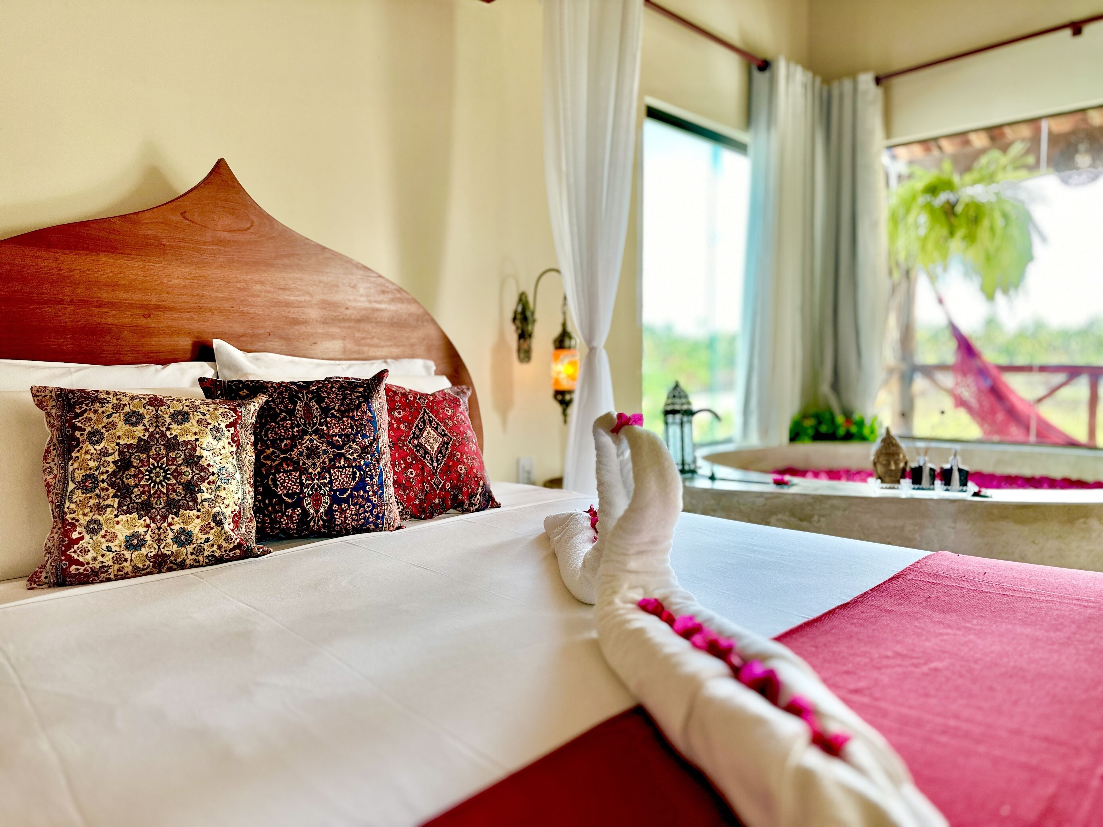 A bed with a wooden headboard, multiple patterned pillows, and a white canopy.