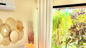 A bedroom with a bed adorned with rose petals, a view of a swimming pool, and a ceiling fan.