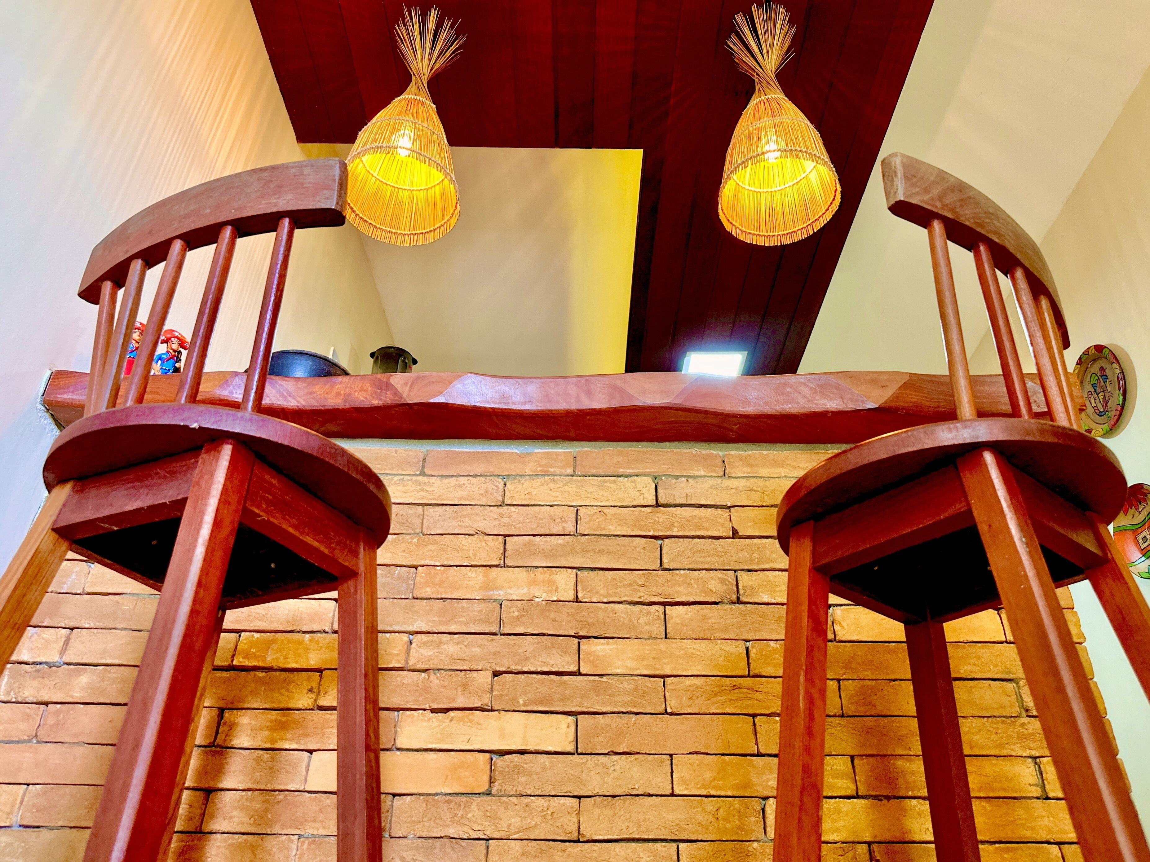 Una escalera de madera con dos sillas de madera en la parte superior, un muro de ladrillo y dos lámparas colgantes.