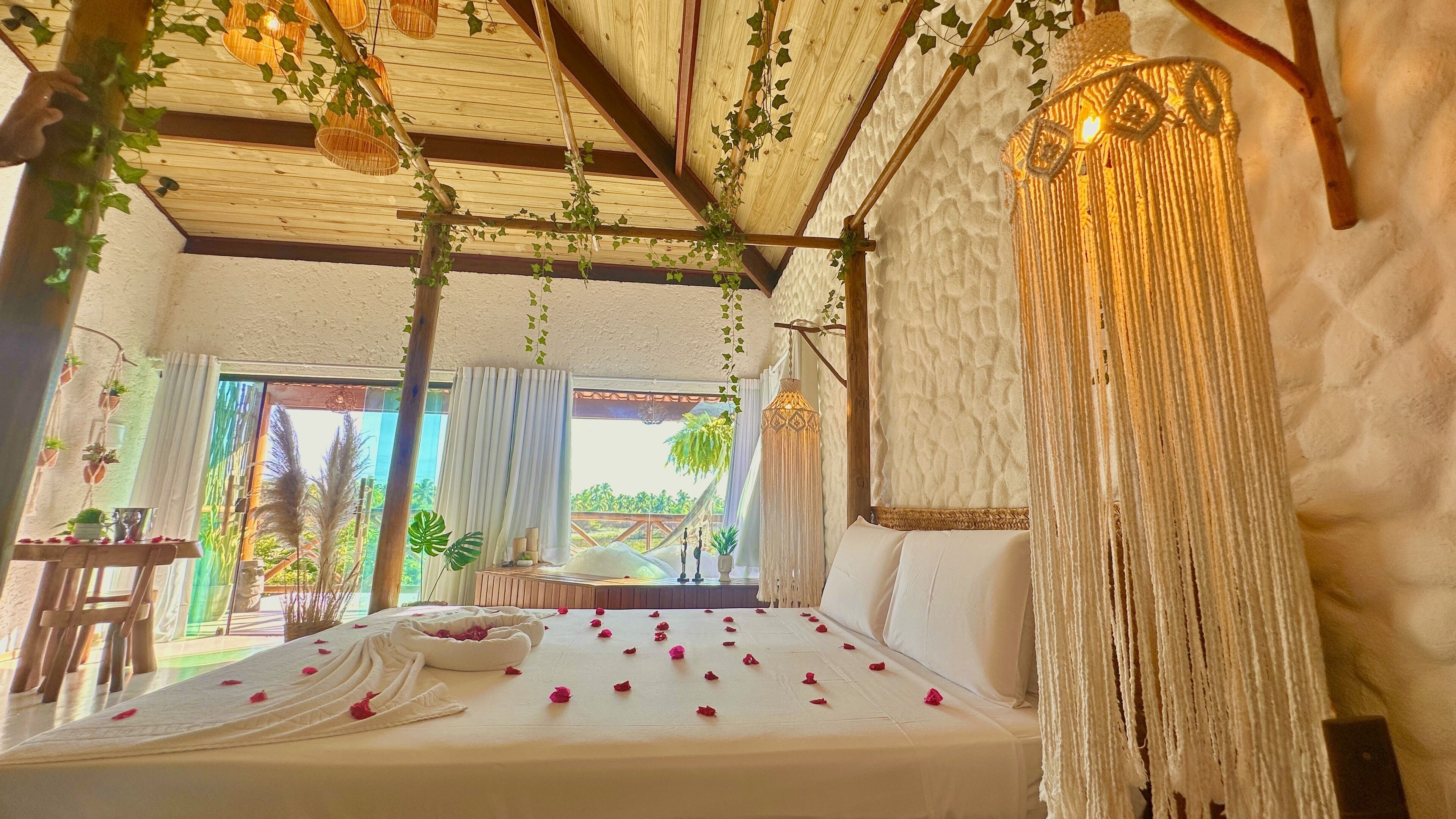 A room with a bed, a hanging light fixture, and a view of the outdoors.