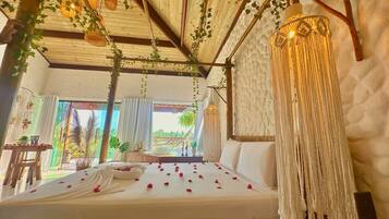 A room with a bed, a hanging light fixture, and a view of the outdoors.