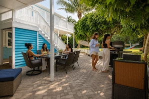 An outdoor patio with a dining table, chairs, and a grill area.